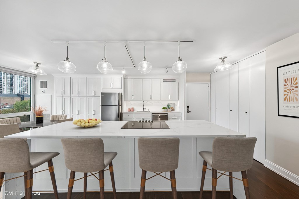 a kitchen with white cabinets and a white counter top and chairs