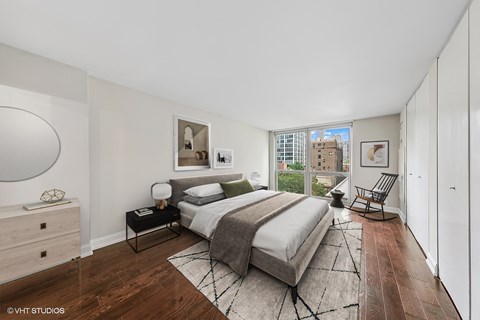 Sunlit bedroom with king bed, hardwood floors, and city view at Astor House, Apartments in Gold Coast Chicago.