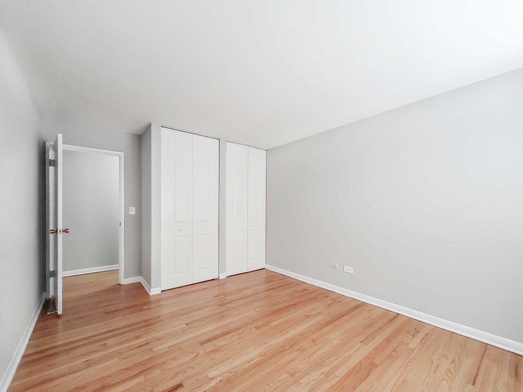 a bedroom with hardwood floors and white walls