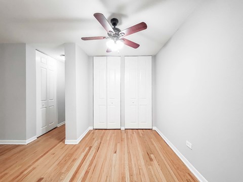 a bedroom with two closets and a ceiling fan