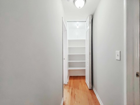 a bedroom with a medium grey wall and a white closet with white shelves