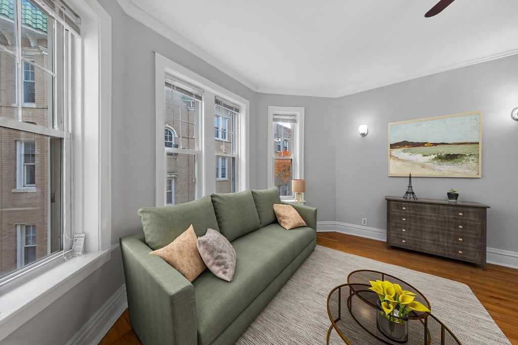 a living room with a green couch and three windows
