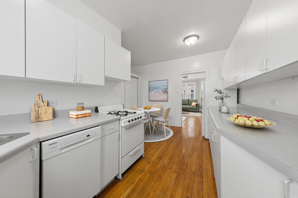 a white kitchen with white appliances and a dining room with a table