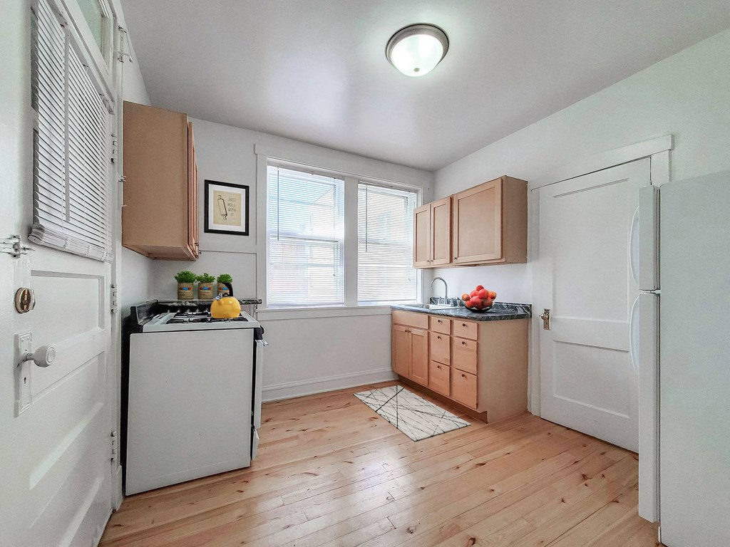 an empty kitchen with wooden floors and white appliances