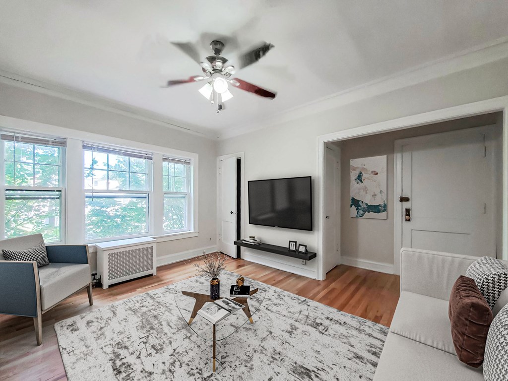 a living room with a ceiling fan and a tv