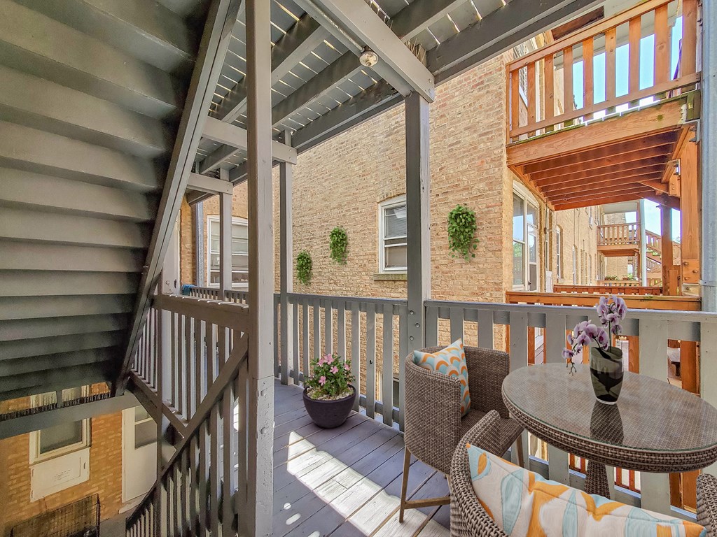 a covered porch with a table and chairs and a brick wall