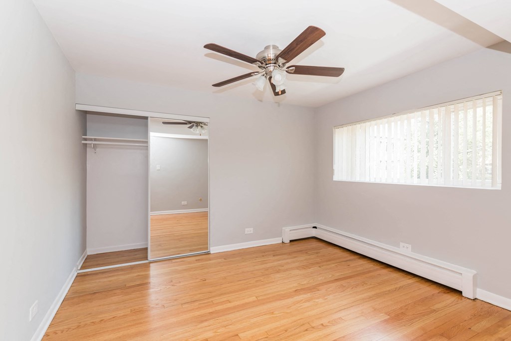 a bedroom with hardwood floors and a ceiling fan