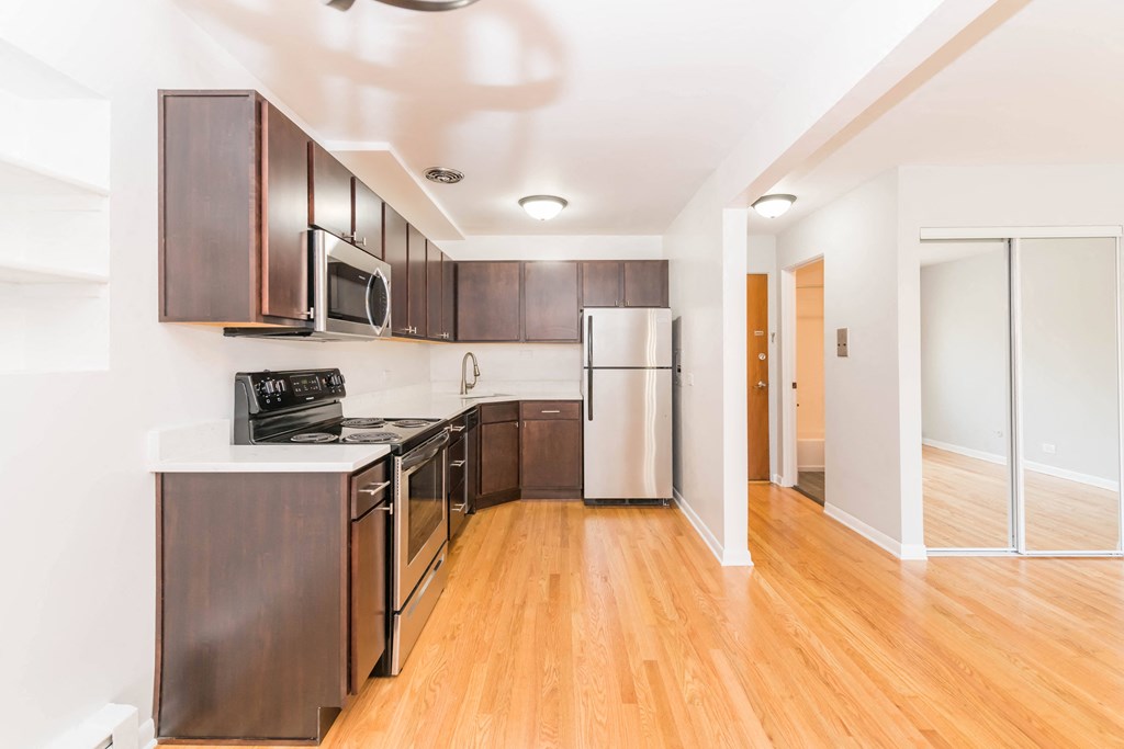 a kitchen with dark wood cabinets and white countertops