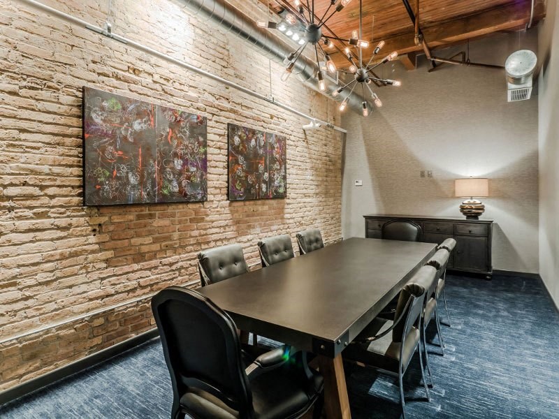 a conference room with a long table and chairs and two paintings on the wall