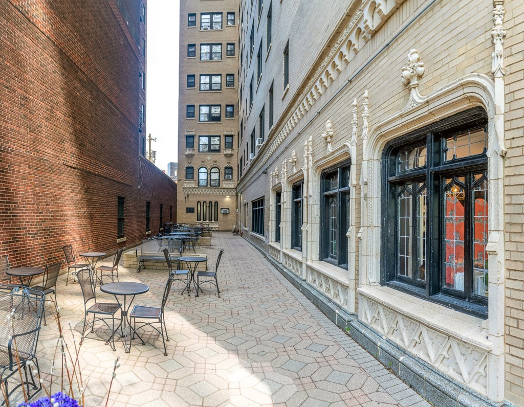 a courtyard with tables and chairs on the side of a building