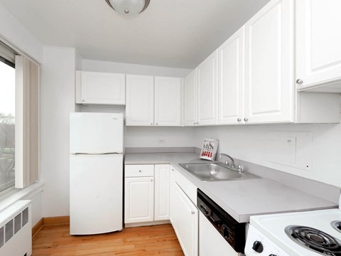 a kitchen with white cabinets and white appliances and a sink