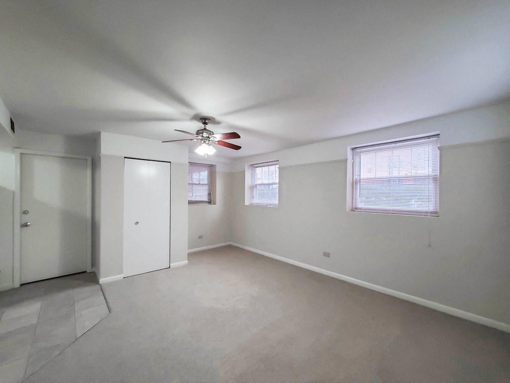 a bedroom with white walls and a ceiling fan