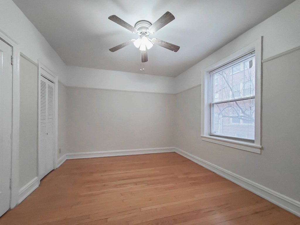 a bedroom with hardwood floors and a ceiling fan
