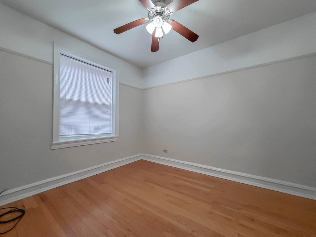 a bedroom with hardwood floors and a ceiling fan