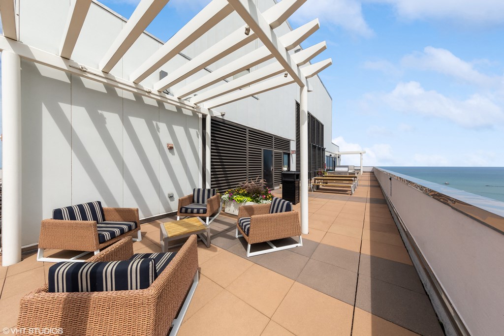 a terrace with wicker chairs and a coffee table with a view of the ocean