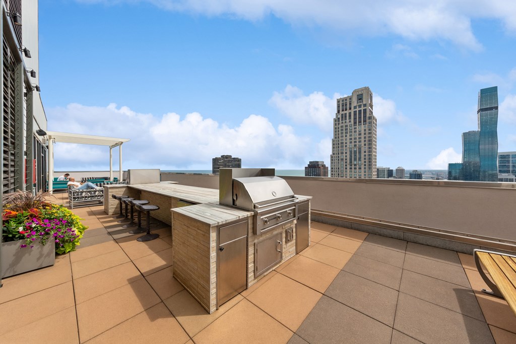 an outdoor barbecue area on the roof of a building with a city skyline in the background