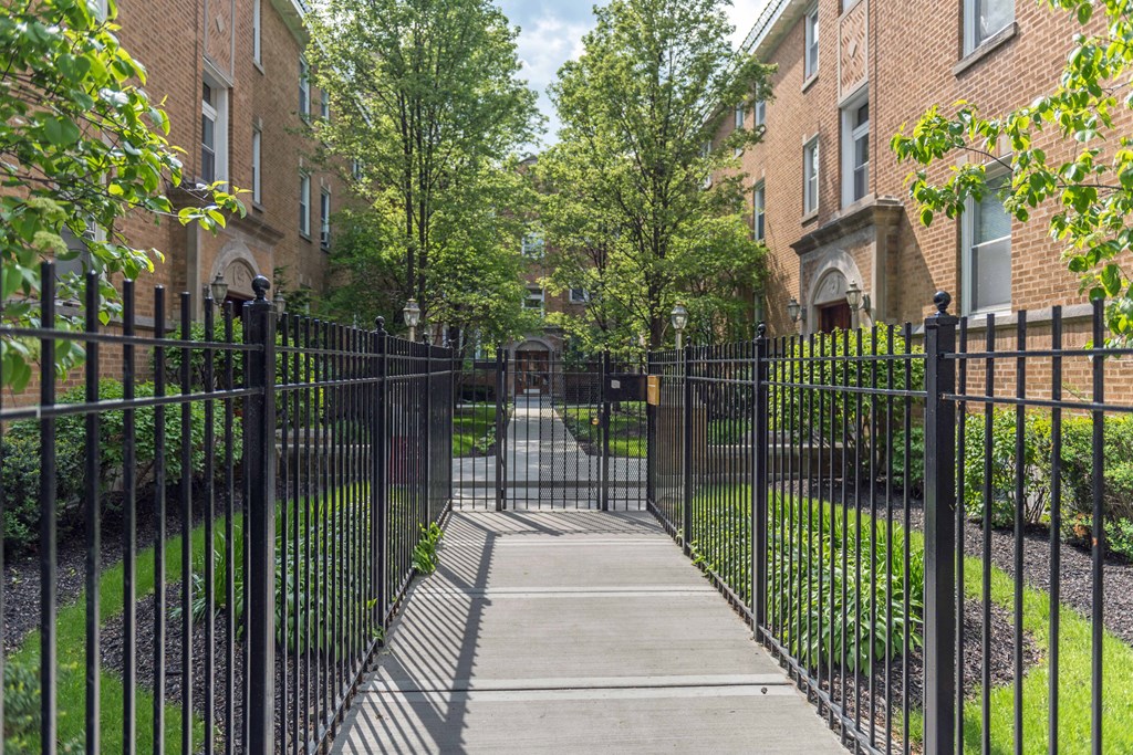 a gated entrance to a brick building with trees in the background