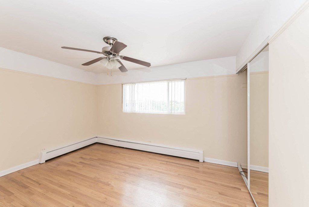 a bedroom with hardwood floors and a ceiling fan