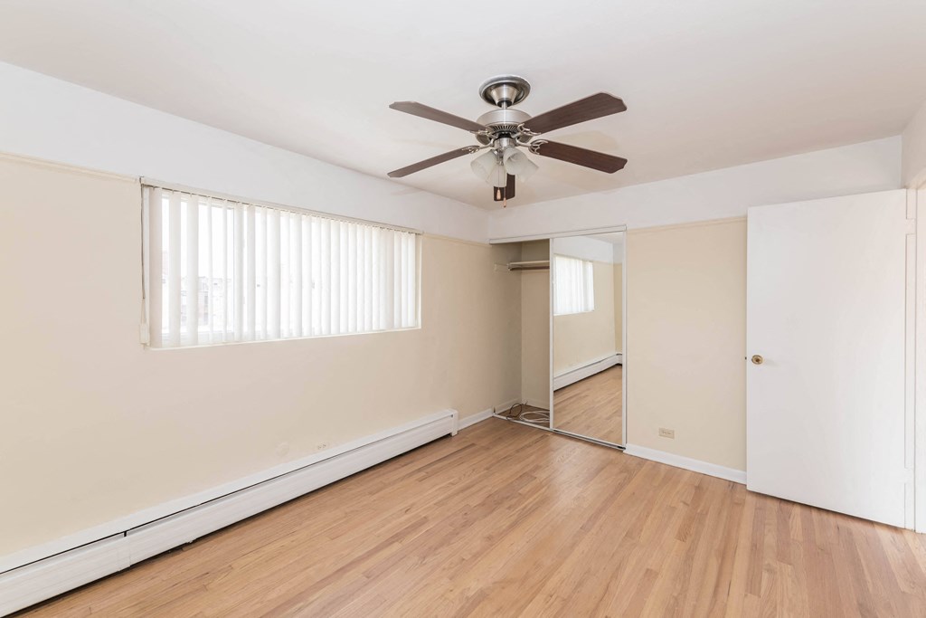 a bedroom with hardwood floors and a ceiling fan
