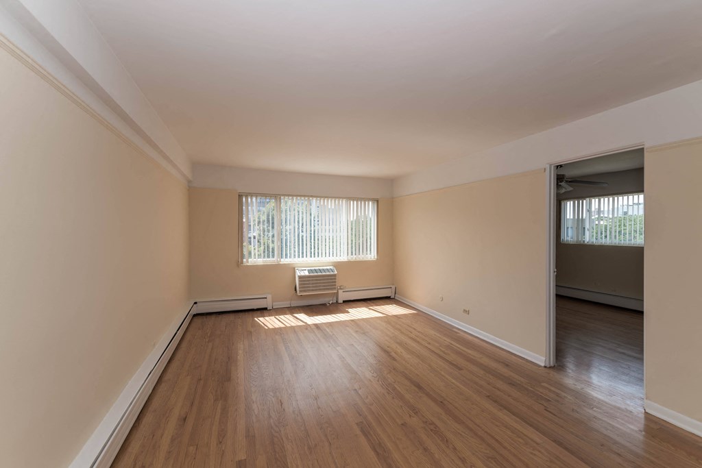 an empty living room with hardwood floors and a large window