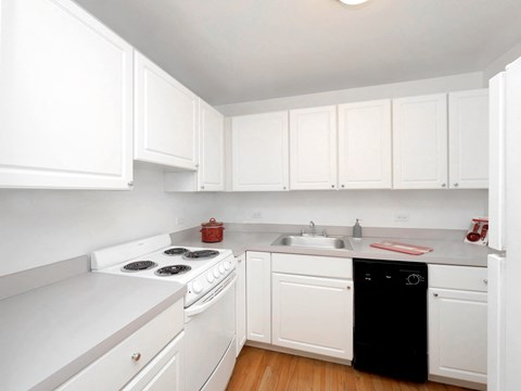Clarendon Shores kitchen with white cabinets, electric stove, stainless sink, and dishwasher.
