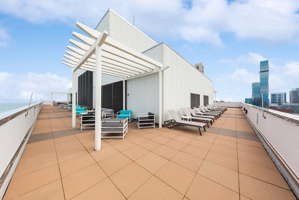 a roof top deck with lounge chairs and a white awning