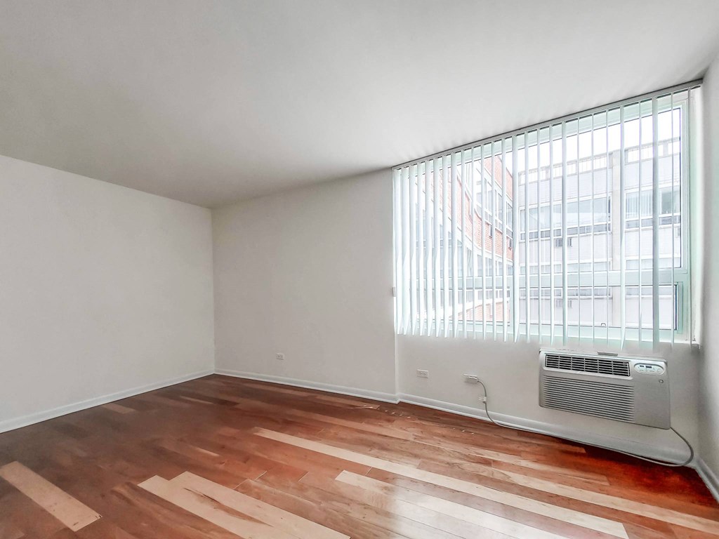 a bedroom with a large window and hardwood floors