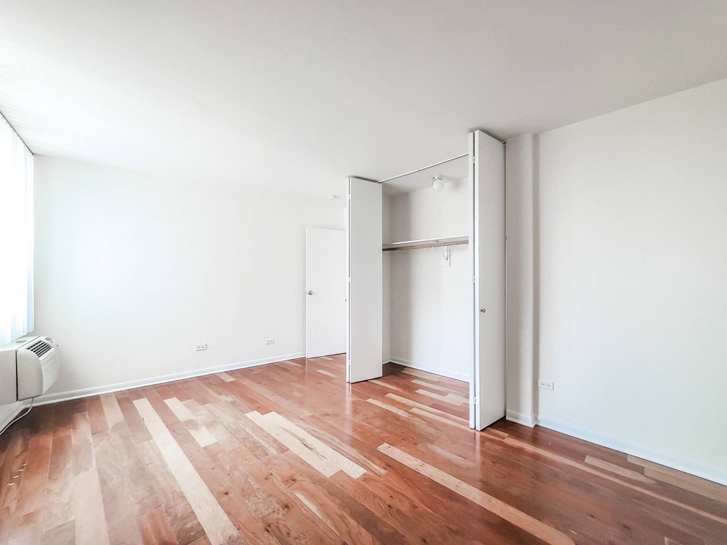 a bedroom with hardwood floors and white walls
