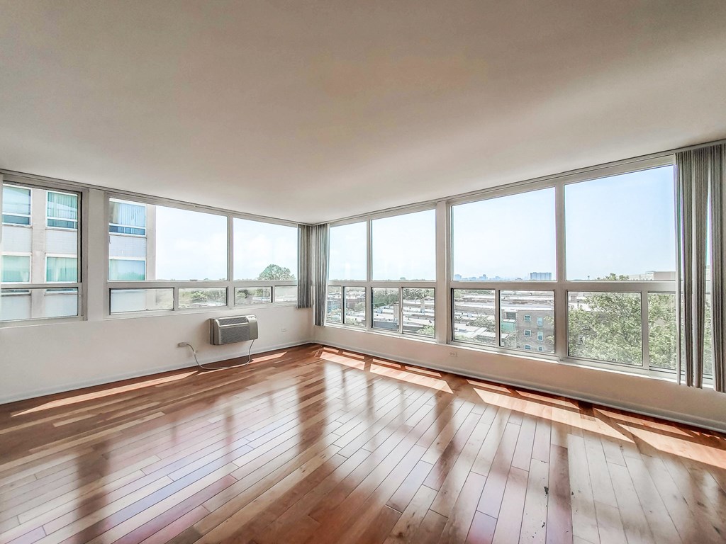 a bedroom with a large window and hardwood floors