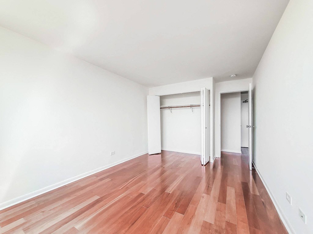 a bedroom with hardwood floors and white walls