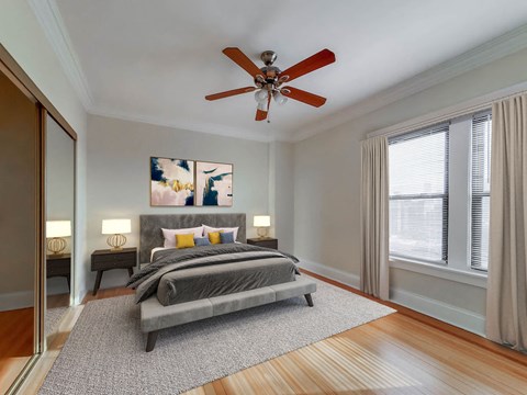 Bedroom at The Patricians, apartments in Lincoln Park Chicago: bed, nightstands, ceiling fan, mirrored closet, large window.