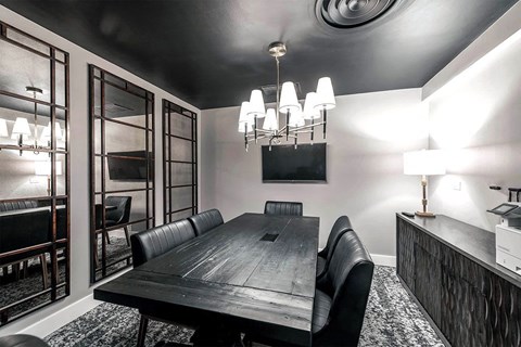 Astor House Apartments in Gold Coast Chicago conference room with long dark wood table, leather chairs and wall-mounted TV.