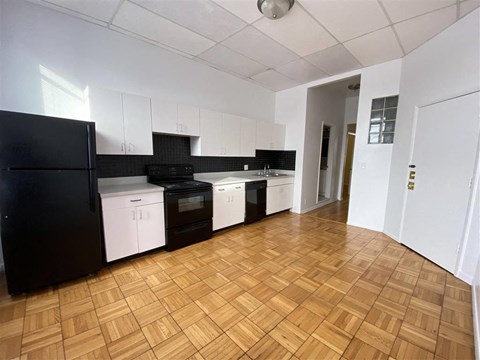 an empty kitchen with white cabinets and black appliances
