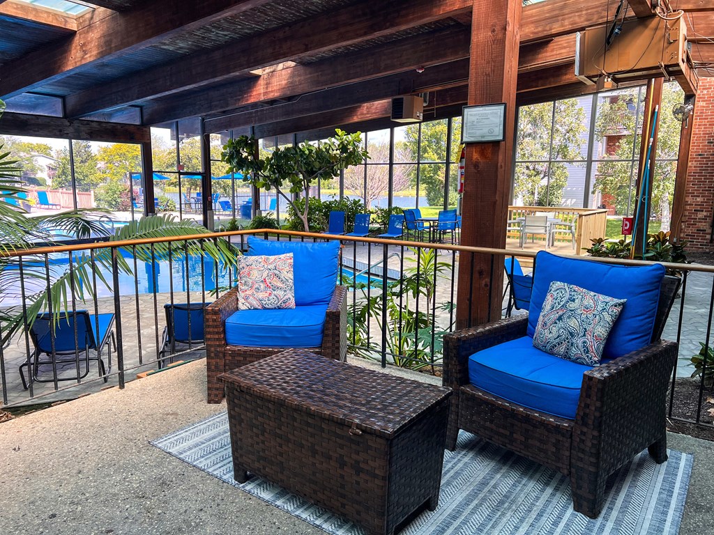 A patio with blue chairs and a wicker table.