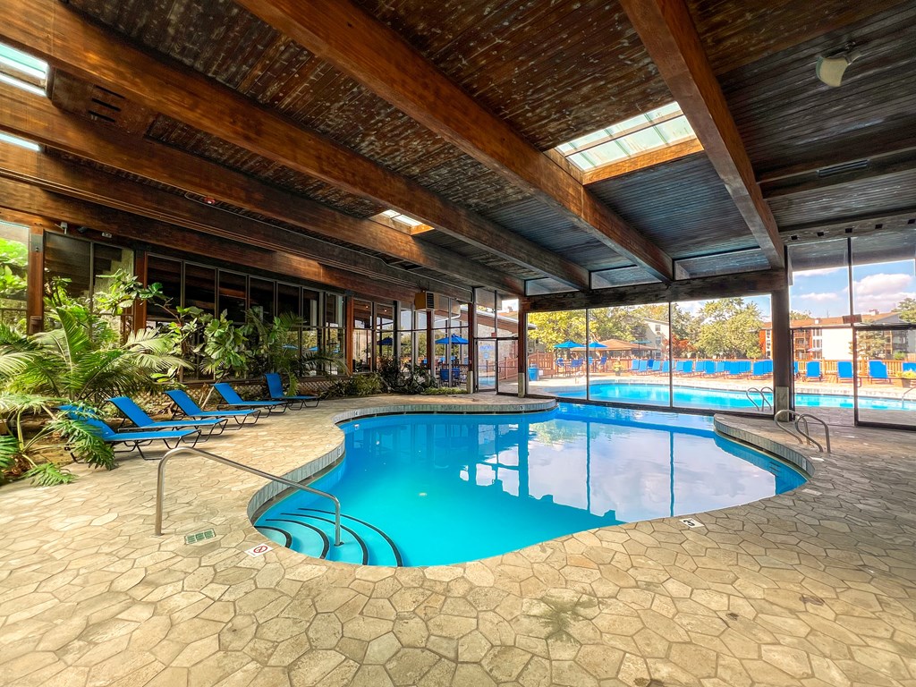 A large indoor swimming pool with a wooden ceiling and tiled floor.