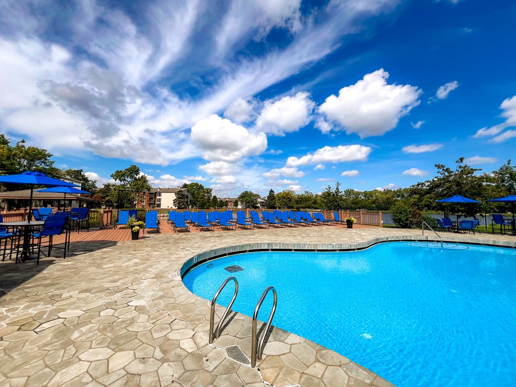 A swimming pool surrounded by blue lounge chairs and umbrellas.
