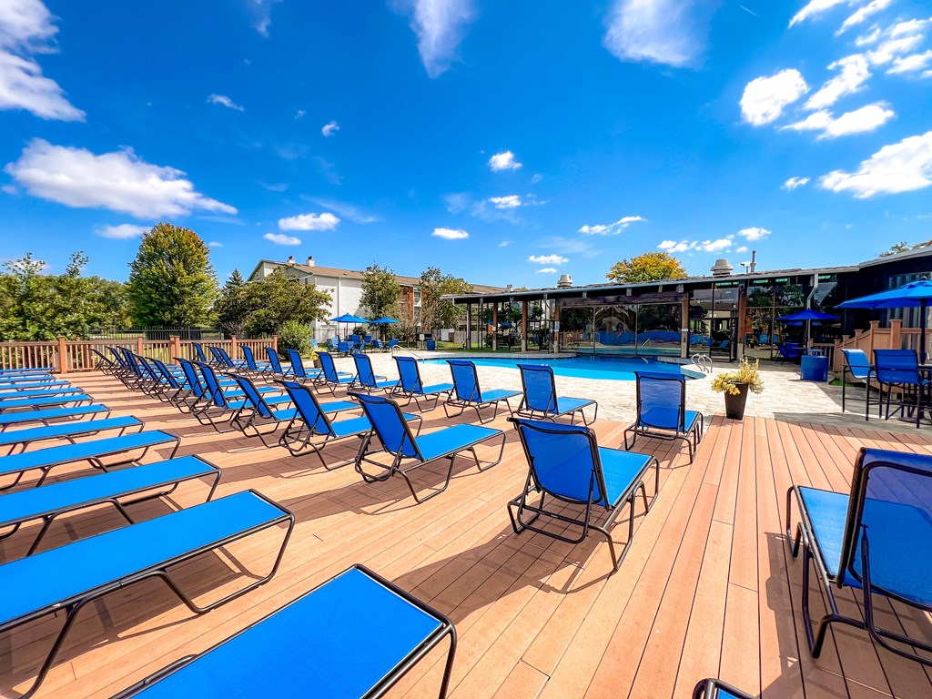 A sunny day at the pool with blue lounge chairs and wooden deck.