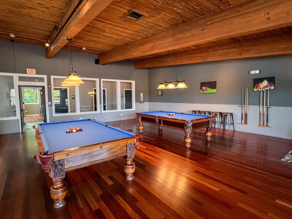 A pool table in a room with wooden floors and a ceiling.