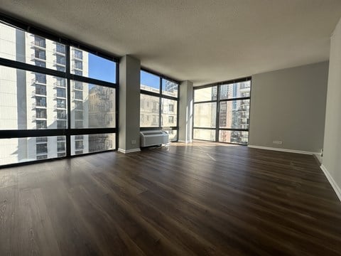 A room with wooden floors and large windows overlooking a cityscape.