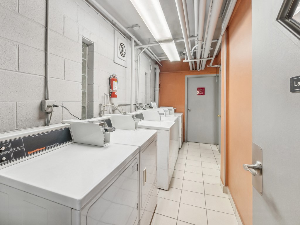 a laundry room filled with white washers and dryers