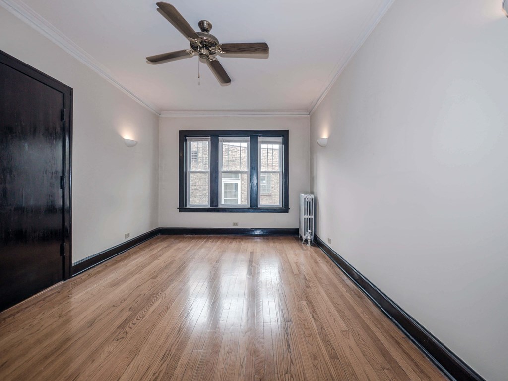 an empty room with hardwood floors and a ceiling fan