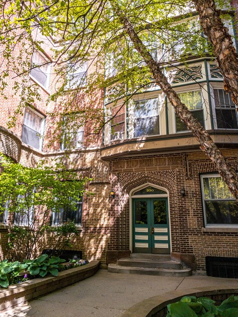 The Pehlam brick entrance with green double doors and shaded courtyard — Apartments in Lincoln Park Chicago.