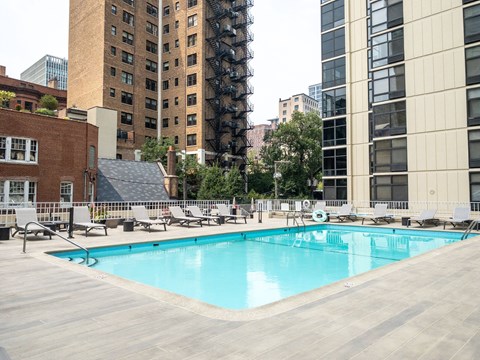 Rooftop pool with lounge chairs at 65 East Scott, Apartments in Gold Coast Chicago, framed by surrounding city buildings.