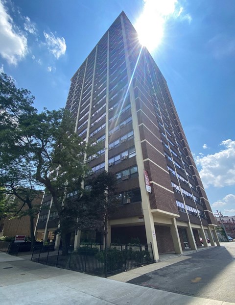 Buena Shores apartments in Buena Park Chicago, tall brick high-rise with street trees and sunlight.