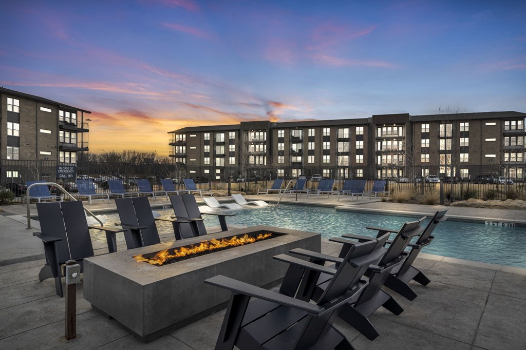 a swimming pool with lounge chairs and a fire pit in front of a building