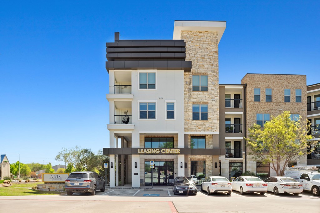 A modern building with a leasing center sign in front.