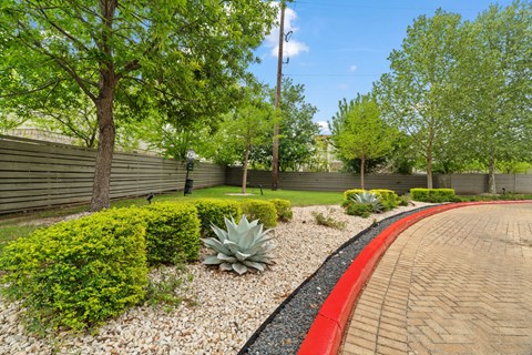 A red brick pathway leads through a well-manicured garden.