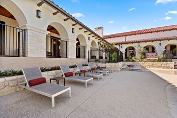 a row of lounge chairs on a patio outside of a building