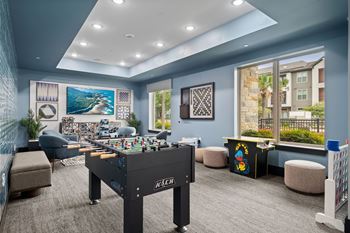 A room with a foosball table and a couch.