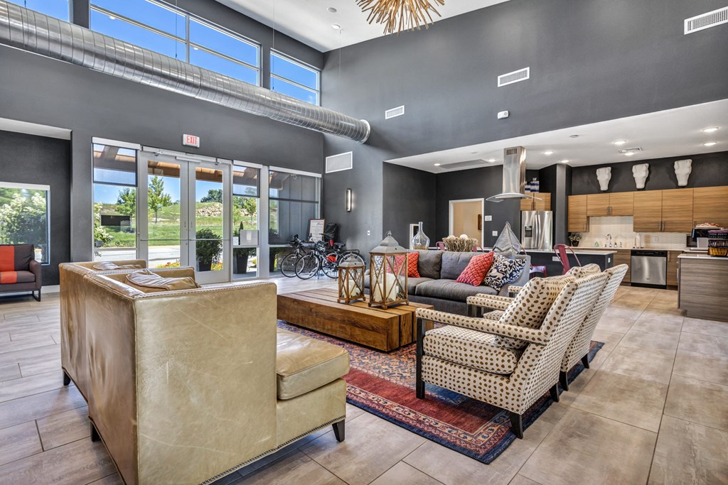 a living room with couches and chairs and a kitchen with windows